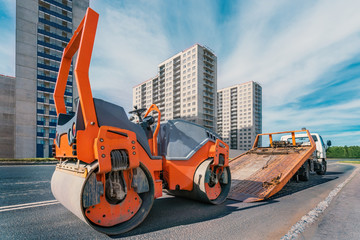 tow truck and asphalt paver on the city road