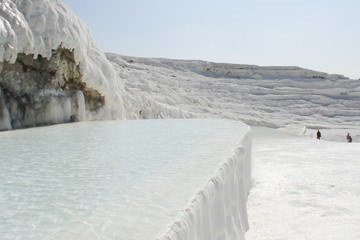 natural bathtub overfilled with pure mineral water; snow-white travertine rocks; famous healing springs in Pamukkale, Türkiye