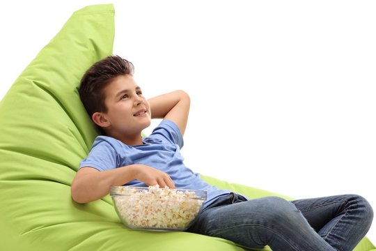 Little boy sitting on a beanbag and eating popcorn