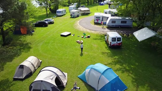 Aerial tents and camper trucks at a big green meadow camping in Czech Republic