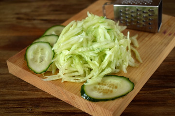 Grated cucumber on a wooden board. Ingredient for a meal