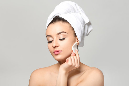 Beautiful Young Woman Using Cotton Pad On Light Background