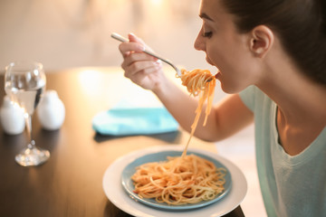 Young woman eating tasty pasta in cafe