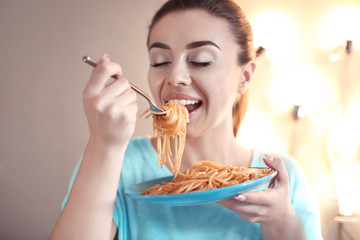 Young woman eating tasty pasta in cafe