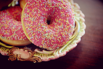 delicious doughnuts decorated by frosted pink glaze and rainbow sugar sprinkles, soft focus