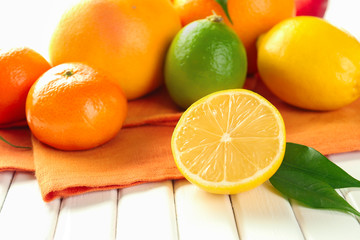 Half of tasty lemon with citrus fruits on table