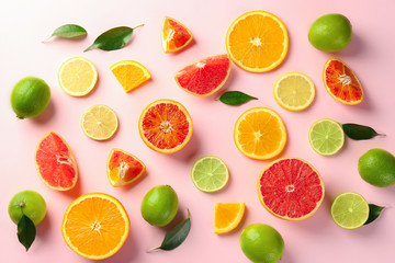 Fototapeta na wymiar Different cut citrus fruits on color background, top view