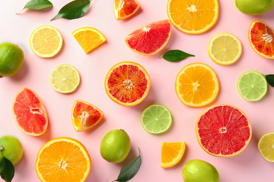 Different cut citrus fruits on color background, top view