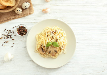 Plate of delicious pasta with mushrooms on white wooden table