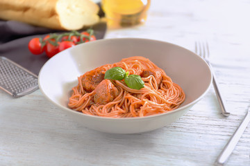 Plate of delicious pasta with meat and tomato sauce on white wooden table