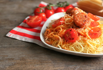 Plate of delicious pasta with meat and tomato sauce on wooden table
