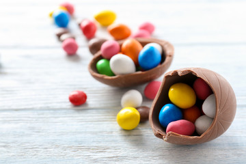 Fototapeta na wymiar Chocolate Easter eggs with colorful candies on white wooden background
