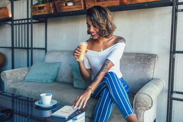 Shot of happy young black cuban woman drinking juice in cafe