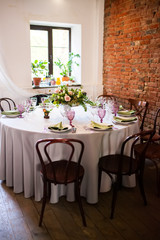 Fototapeta na wymiar Wedding banquet, loft style, served tables with flowers and lots of greenery.