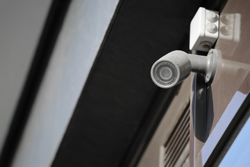 Modern CCTV camera on wall of building outdoors