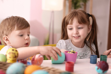 Fototapeta premium Cute kids painting Easter eggs together at table