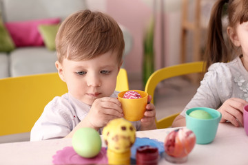 Cute kids painting Easter eggs together at table