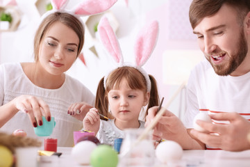 Family painting Easter eggs together at table