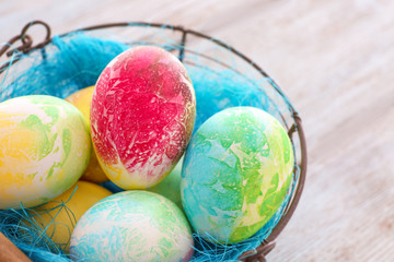 Basket with colorful Easter eggs on table, closeup