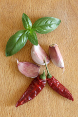 garlic cloves, basil leaves and  hot chili pepper on a wooden cutboard