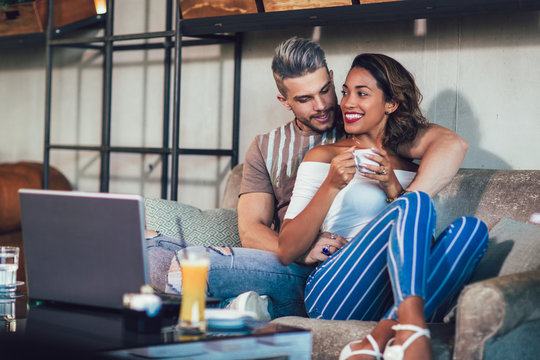 Young interracial couple spending time in cafe watching media together on laptop.