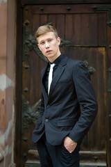 Handsome young man in trendy black suit and tie posing