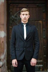 Handsome young man in trendy black suit and tie posing