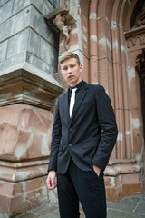 Handsome young man in trendy black suit and tie posing