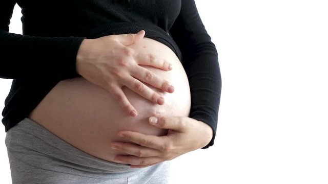 Close up pregnant woman showing her belly to the camera isolated on white background