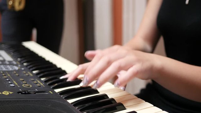 Closeup female musician fingers play music on a piano synthesizer