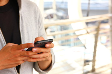 man in gray cloth is using mobile in his hand