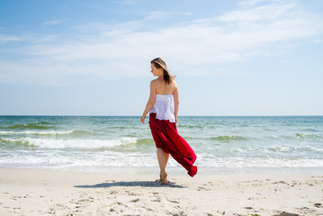 Beautiful girl in red dress by the sea.