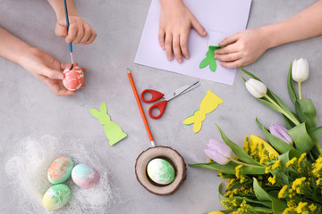 Little children painting eggs and making Easter decorations at table