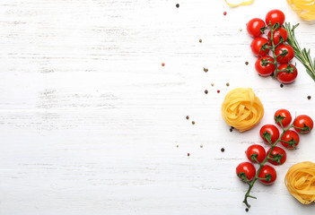 Uncooked pasta and cherry tomatoes on wooden background