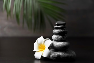 Obraz na płótnie Canvas Stack of spa stones and beautiful flower on dark table