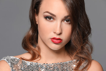 Portrait of young woman with beautiful professional makeup on grey background, closeup