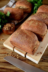 Loaves of rye bread sprinkled with coriander on a wooden board