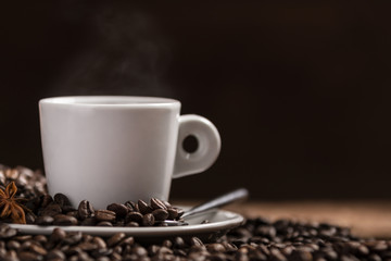 Cup of hot coffee with coffee beans on wooden table