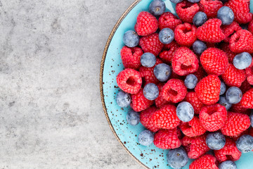 Fresh raspberries in a plate on a  vintage background.