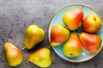 Fresh bio pear with leaves on the plate. Gray stone table.