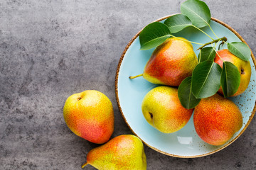 Fresh bio pear with leaves on the plate. Gray stone table.