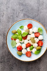 Delicious caprese salad with ripe cherry tomatoes and mini mozzarella cheese balls with fresh basil leaves.