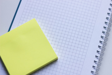 Blank yellow stick note on a spiral notebook from above. Removable self-stick notes
