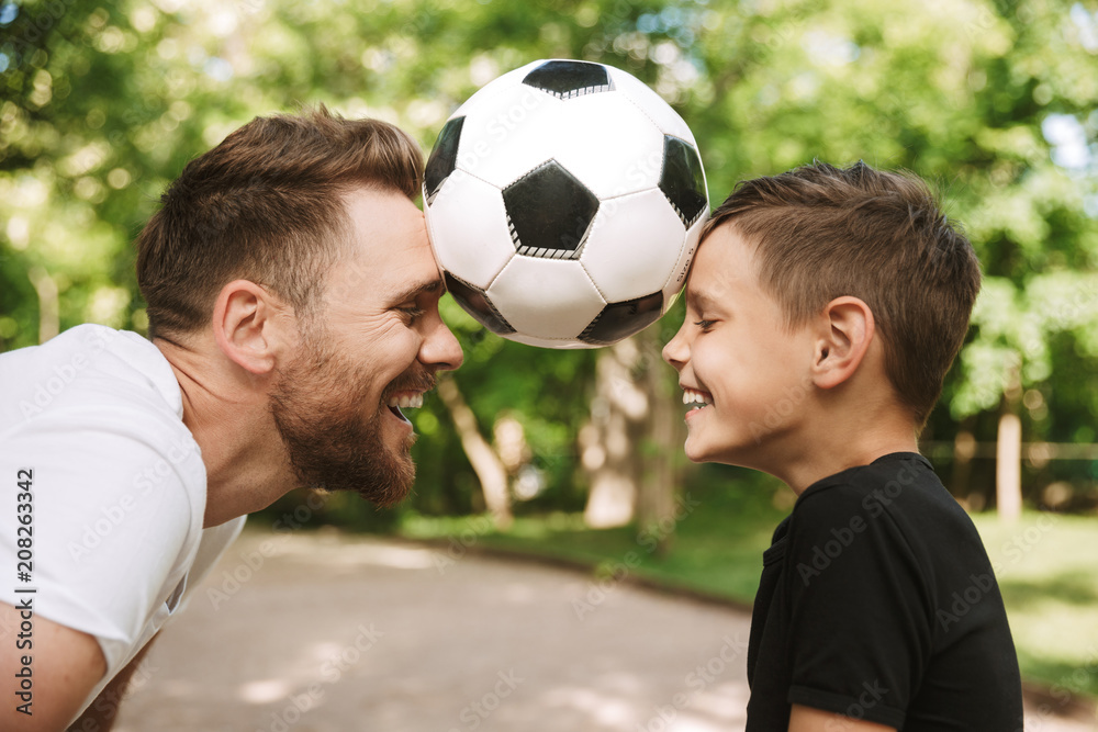 Wall mural Happy young father have fun with his little son with football