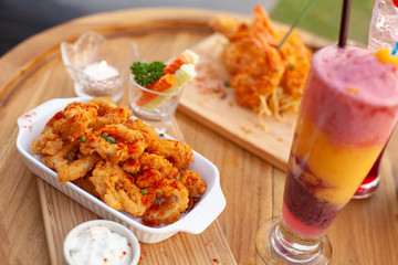 Close up to appetizer calamari and fried shrimp on tray with colourful smoothy.