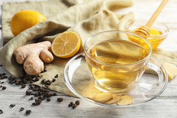 Cup of delicious tea with lemon, ginger and honey on table