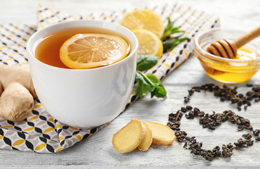 Cup of delicious tea with lemon, ginger and honey on table