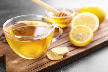 Cup of delicious tea with lemon and ginger on wooden board