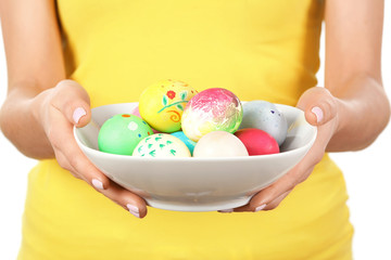 Fototapeta na wymiar Young woman with bowl full of colorful Easter eggs, closeup