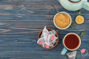Tea bags, sugar and mug with hot beverage on table